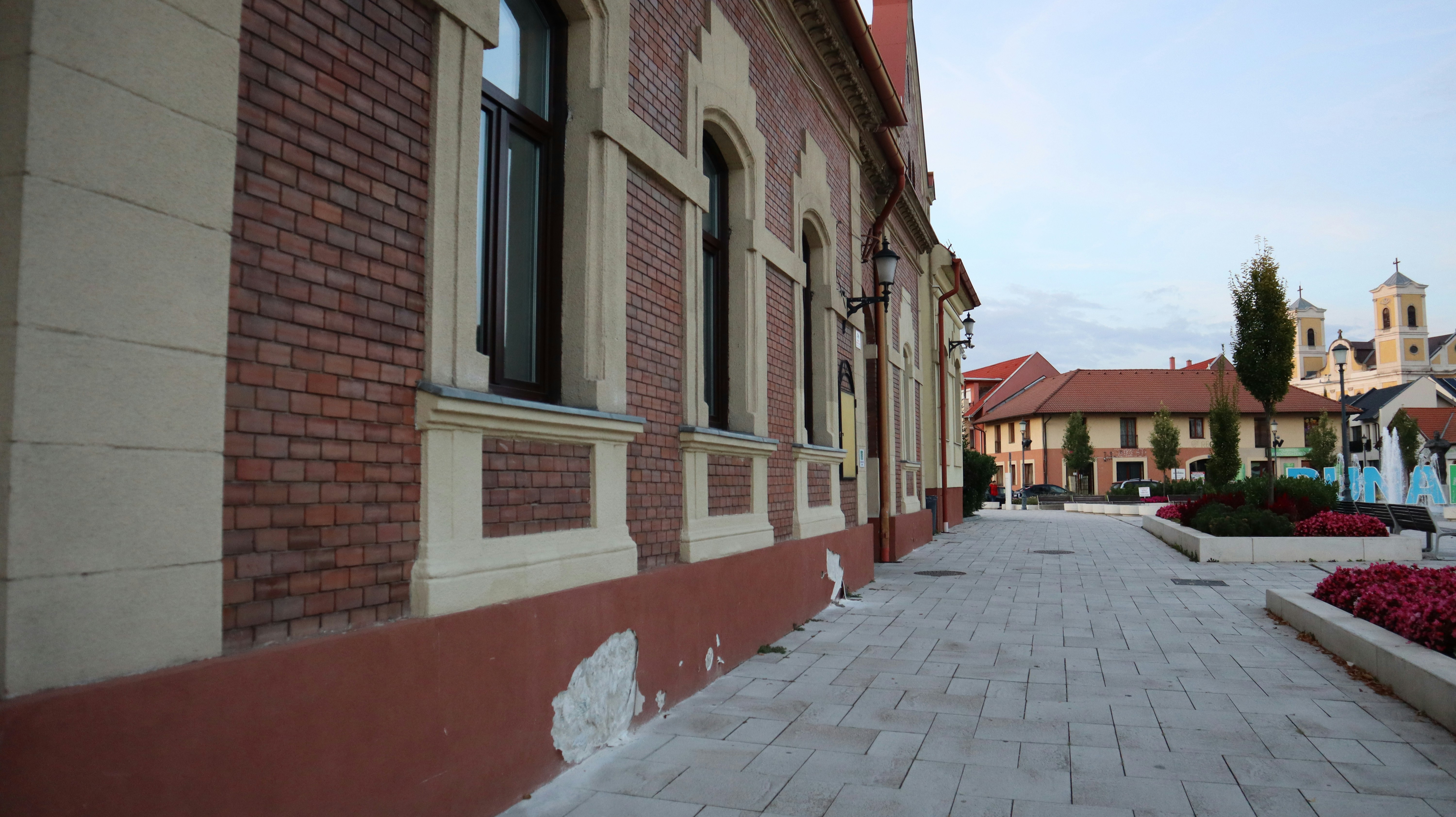 a brick walkway between two buildings with a clock tower in the background